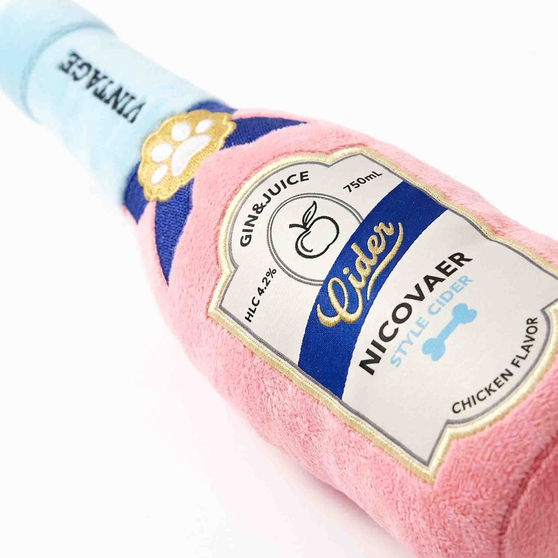 Close-up of pink cider bottle plush dog toy label – detailed embroidered with paw print and chicken flavor parody on soft squeaky plush by PetsFave